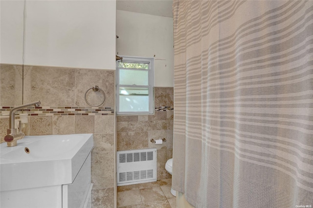 bathroom featuring vanity, toilet, radiator heating unit, and tile walls