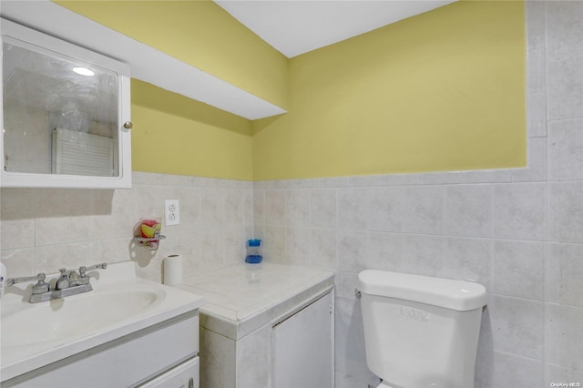 bathroom featuring vanity, tile walls, and toilet