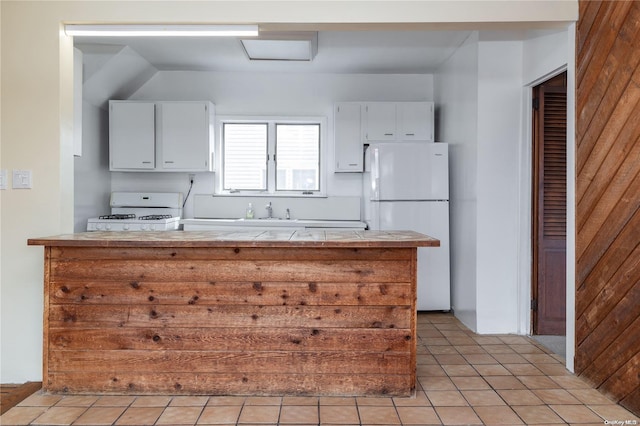 kitchen featuring white cabinetry, light tile patterned floors, white appliances, and wooden walls