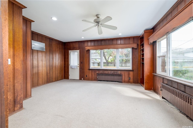 living room with a wealth of natural light, radiator, and wood walls