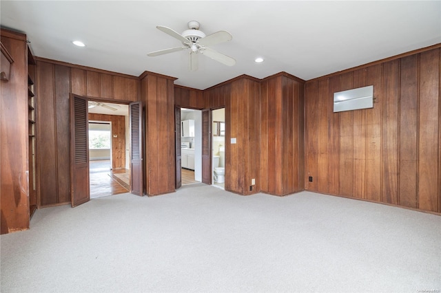 spare room with ceiling fan, wood walls, and light colored carpet