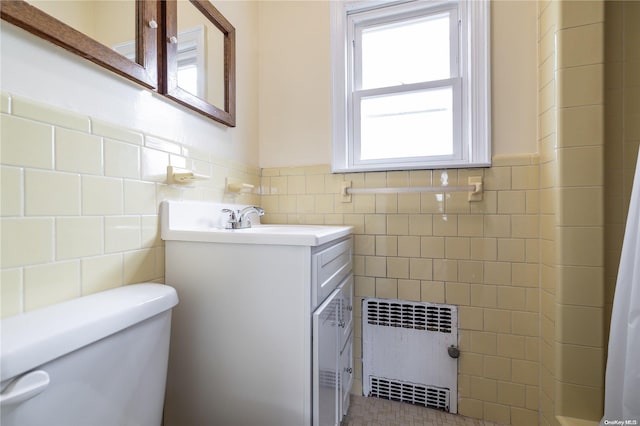 bathroom with vanity, toilet, radiator, and tile walls