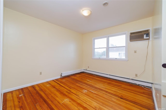 spare room featuring a baseboard radiator, a wall mounted air conditioner, and hardwood / wood-style flooring