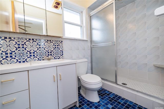 bathroom featuring tasteful backsplash, tile patterned flooring, toilet, vanity, and tile walls