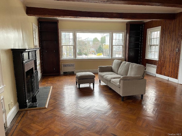 living room with radiator, wood walls, dark parquet flooring, and beamed ceiling