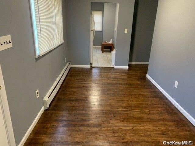 unfurnished room with a baseboard radiator and dark hardwood / wood-style floors