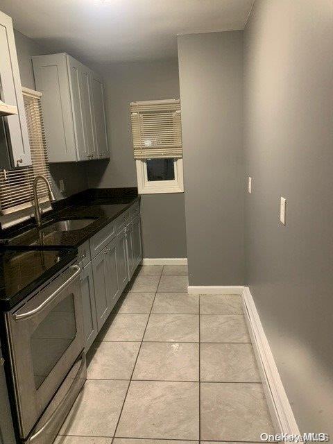 kitchen with gray cabinetry, stainless steel range, sink, light tile patterned floors, and white cabinetry