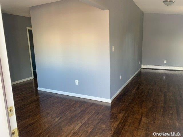 empty room with dark hardwood / wood-style flooring and a baseboard radiator