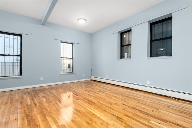 empty room featuring beam ceiling, light wood-type flooring, and a baseboard radiator