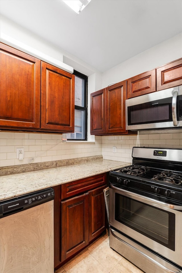 kitchen with light tile patterned floors, backsplash, stainless steel appliances, and light stone counters