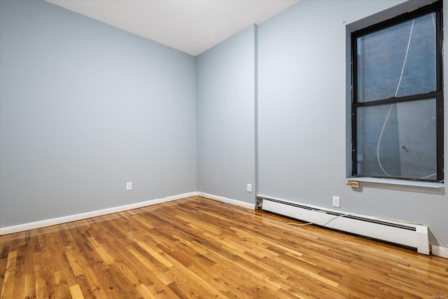 empty room featuring hardwood / wood-style flooring and baseboard heating