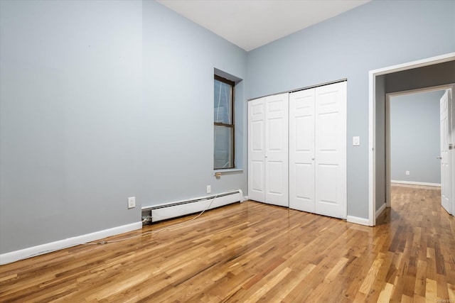 unfurnished bedroom featuring light hardwood / wood-style floors, baseboard heating, and a closet