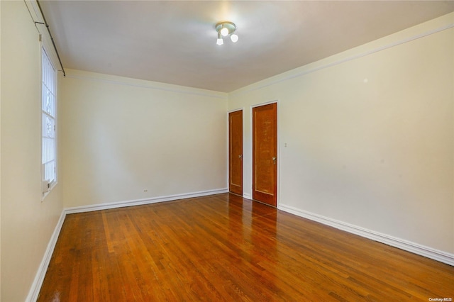 spare room with crown molding and dark wood-type flooring