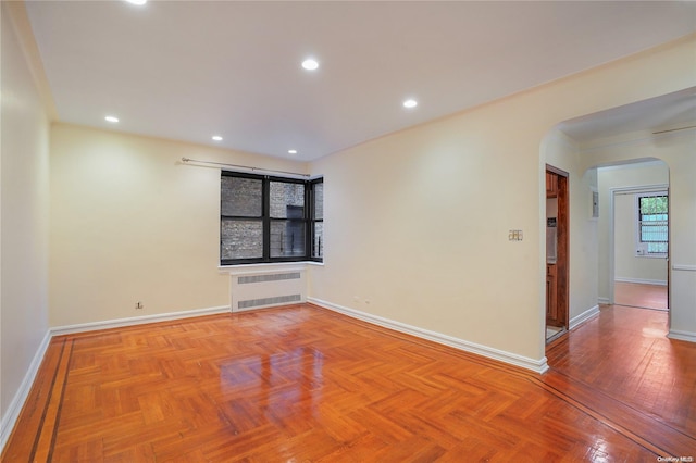 spare room with radiator heating unit and light parquet flooring