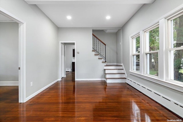 interior space with dark hardwood / wood-style flooring, a wealth of natural light, and a baseboard heating unit