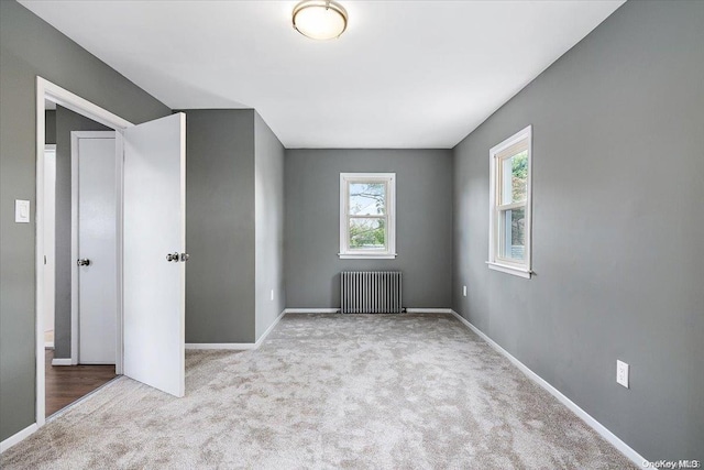 unfurnished bedroom with radiator heating unit and light colored carpet