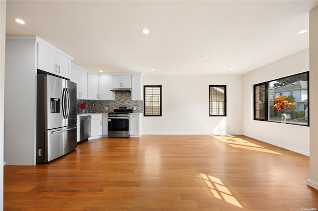 kitchen featuring tasteful backsplash, white cabinetry, light hardwood / wood-style flooring, and stainless steel appliances