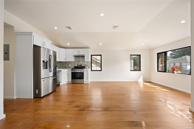 kitchen with light countertops, appliances with stainless steel finishes, open floor plan, white cabinets, and electric panel