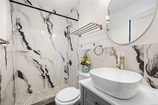 bathroom with toilet, vanity, and a marble finish shower