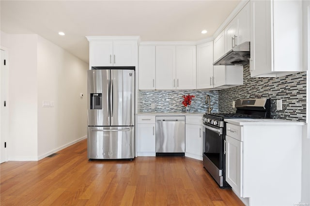 kitchen with stainless steel appliances, light countertops, decorative backsplash, white cabinets, and under cabinet range hood