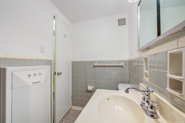 bathroom featuring tile patterned floors, tile walls, and sink