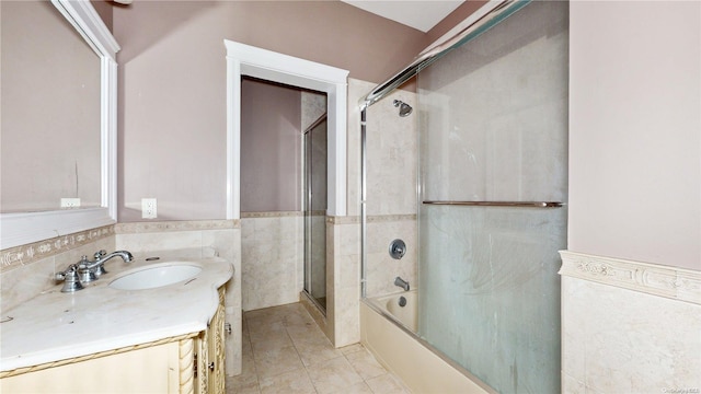 bathroom with tile patterned floors, vanity, shower / bath combination with glass door, and tile walls