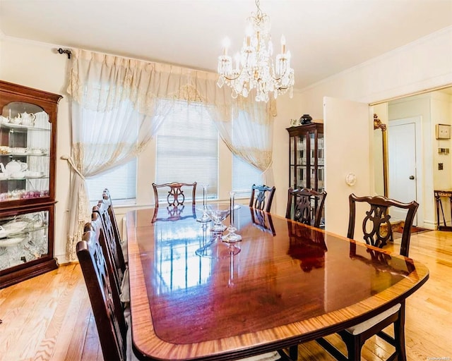 dining area with crown molding, light hardwood / wood-style floors, and a notable chandelier