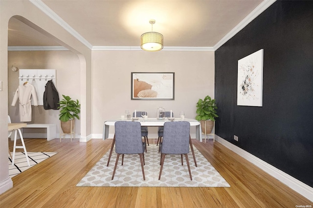 dining room with light wood-type flooring and crown molding