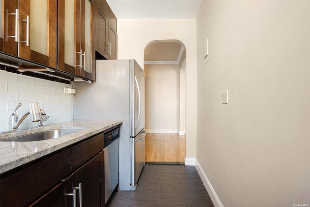 kitchen featuring dishwasher, sink, decorative backsplash, light stone counters, and dark brown cabinetry