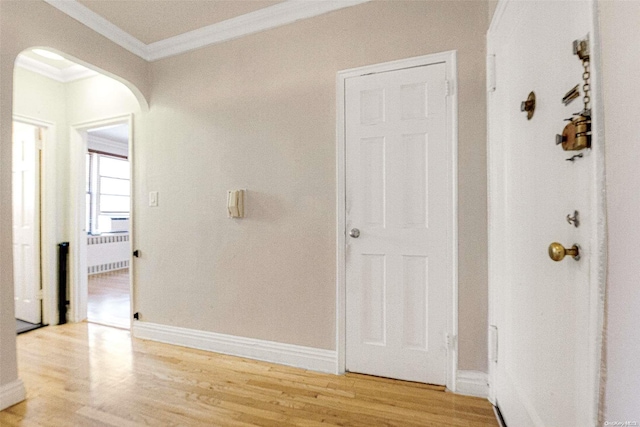 corridor with light hardwood / wood-style floors, radiator, and ornamental molding