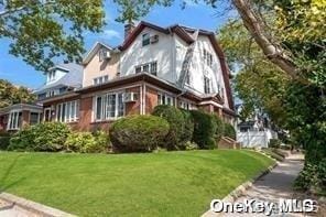 view of side of home with a chimney, a gambrel roof, and a yard