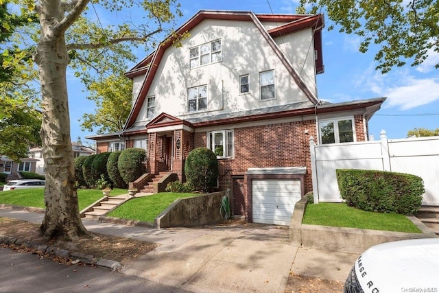 view of front facade with a garage, concrete driveway, a gambrel roof, fence, and brick siding