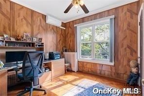 office space with a ceiling fan, ornamental molding, and wooden walls