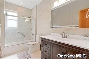 bathroom with toilet, enclosed tub / shower combo, and vanity