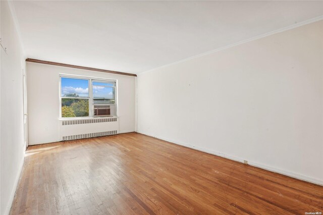 unfurnished room featuring hardwood / wood-style floors, radiator heating unit, and ornamental molding