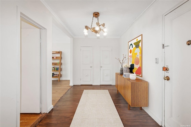 entrance foyer with ornamental molding, dark wood-type flooring, and an inviting chandelier