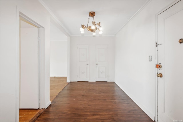 hall featuring dark hardwood / wood-style floors, ornamental molding, and an inviting chandelier