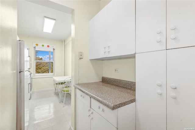 kitchen with white cabinetry, stainless steel refrigerator, and light tile patterned flooring