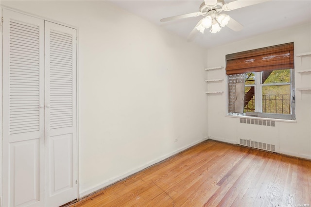 unfurnished bedroom with a closet, light hardwood / wood-style floors, radiator, and ceiling fan