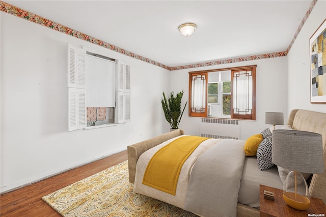 bedroom with radiator and hardwood / wood-style flooring