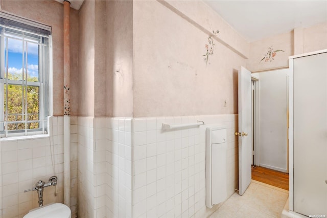 bathroom with tile patterned floors, a healthy amount of sunlight, and tile walls