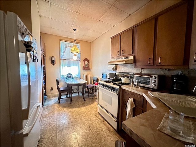 kitchen with backsplash, light tile patterned floors, pendant lighting, and white appliances