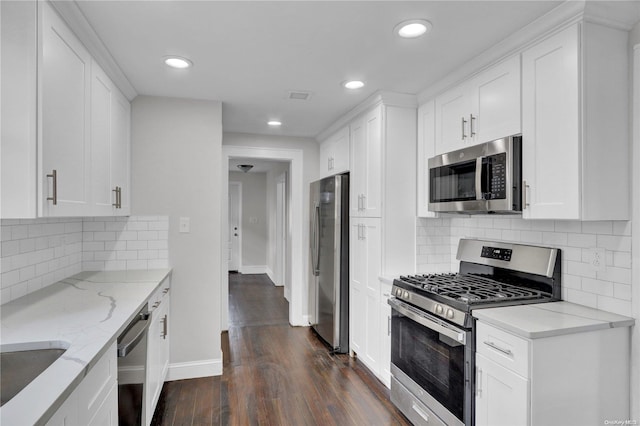 kitchen with light stone counters, white cabinets, dark hardwood / wood-style floors, and appliances with stainless steel finishes