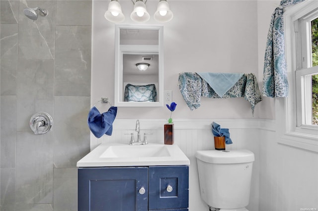 bathroom featuring tiled shower, vanity, and toilet