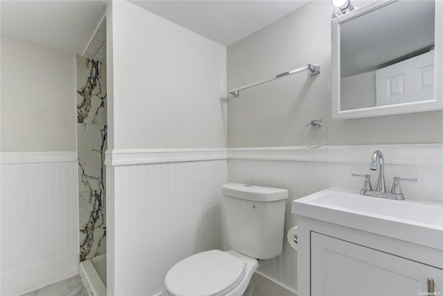 bathroom featuring a tile shower, vanity, and toilet