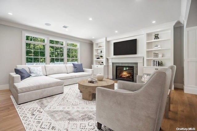 living room with built in shelves, wood-type flooring, and crown molding