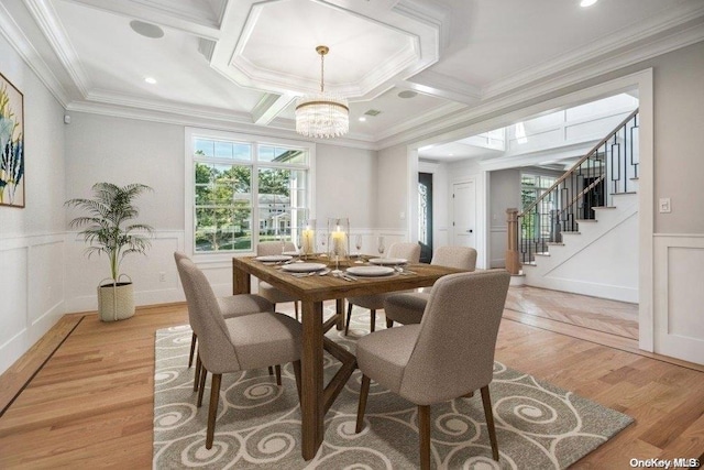 dining room featuring crown molding, light hardwood / wood-style flooring, and coffered ceiling