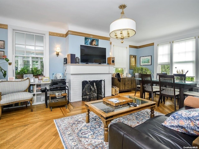 living room with a brick fireplace, a notable chandelier, and light hardwood / wood-style flooring