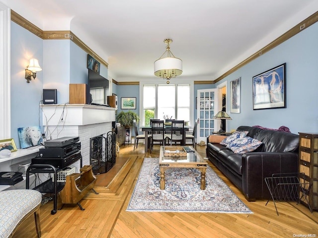 living room with a brick fireplace, light hardwood / wood-style flooring, and ornamental molding