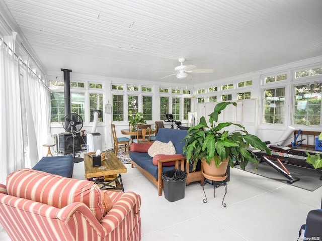 sunroom / solarium featuring a wood stove, a wealth of natural light, and ceiling fan